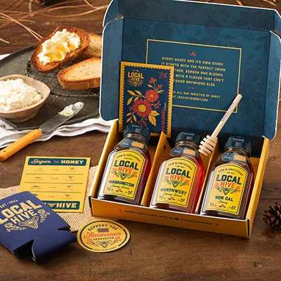 A decorative gift box with honey samples in it.